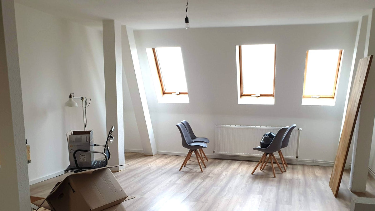 Bright nearly empty apartment with skylights, chairs, and moving boxes ready for a viewing