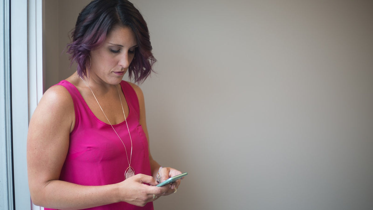 A woman sending a message on her phone to make a clear, practical request for help