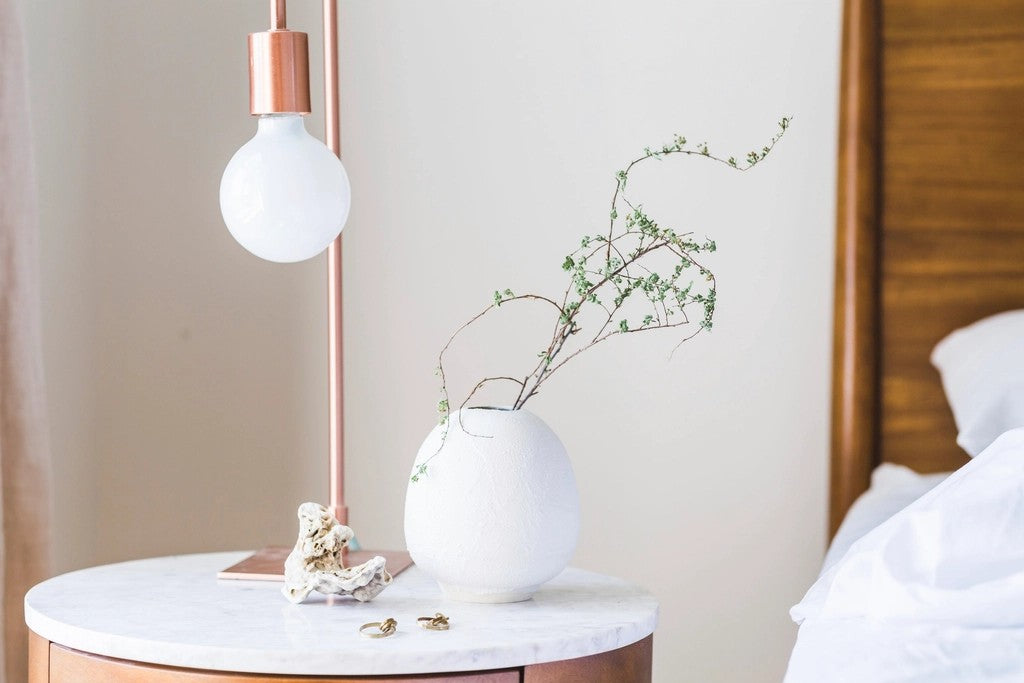 Bright bedside table with a lamp beside neatly made bedding
