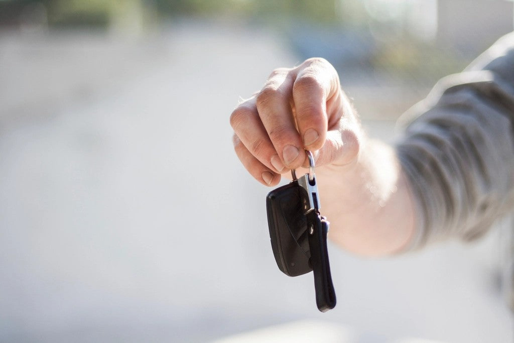Close-up of a person holding two black car keys against a softly blurred background