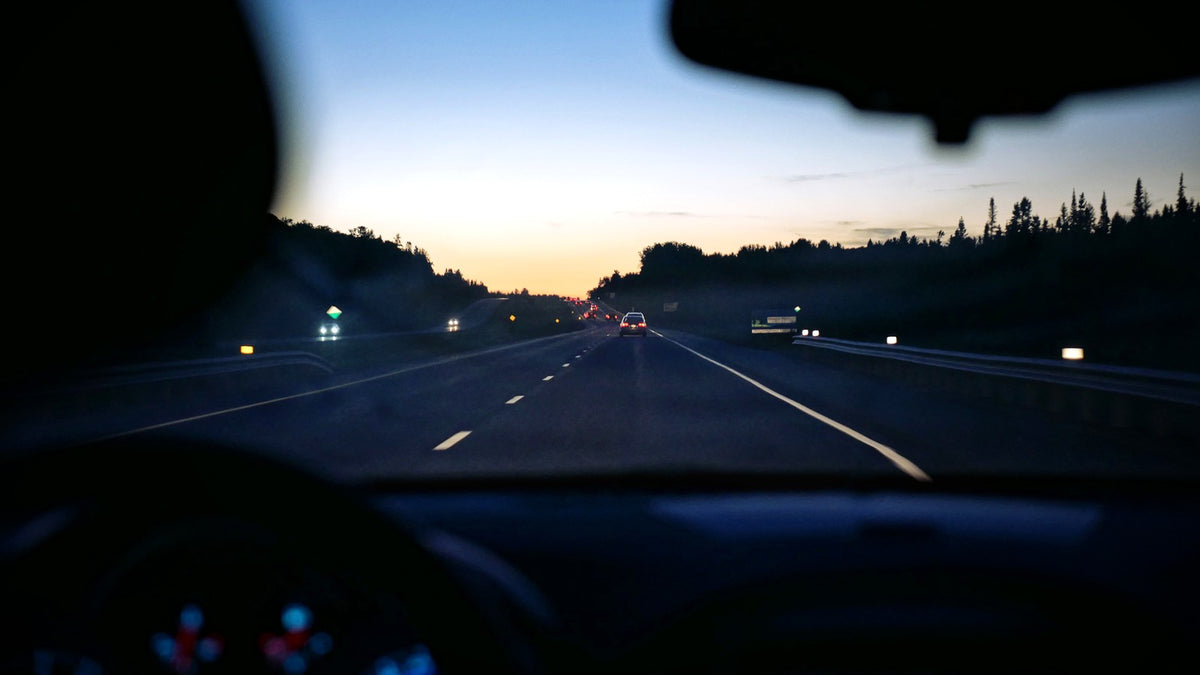 View from inside a car traveling on a highway near sunset
