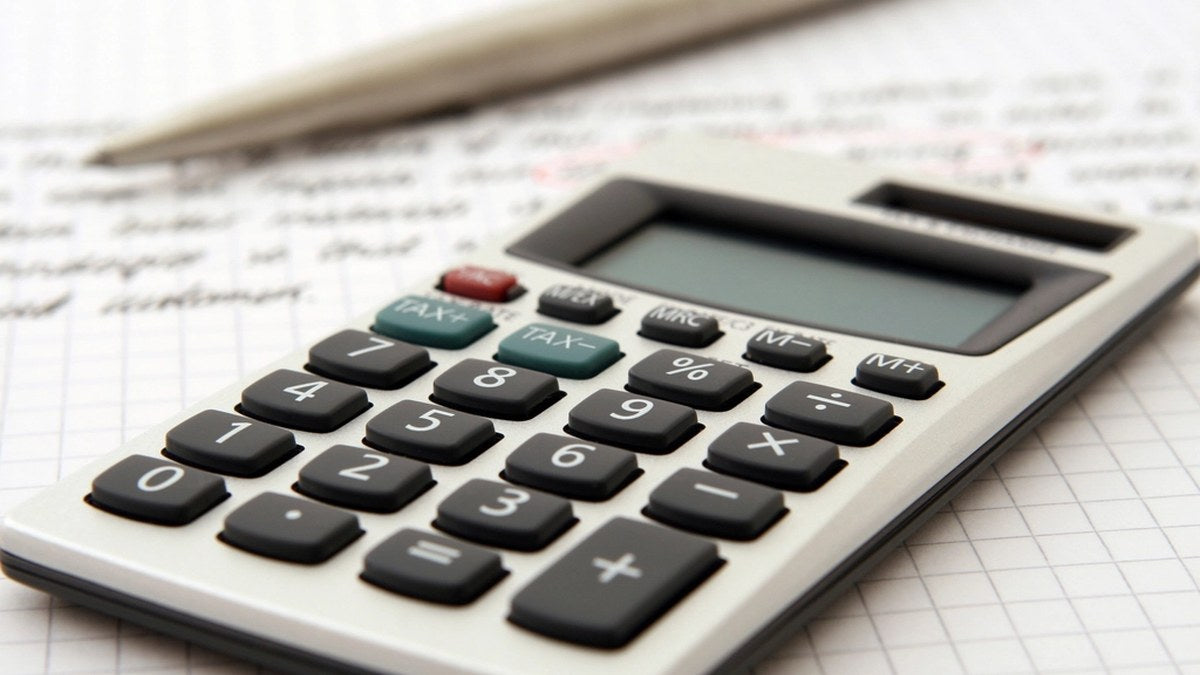 A simple calculator resting on grid paper with a pencil nearby, ready for quick price math