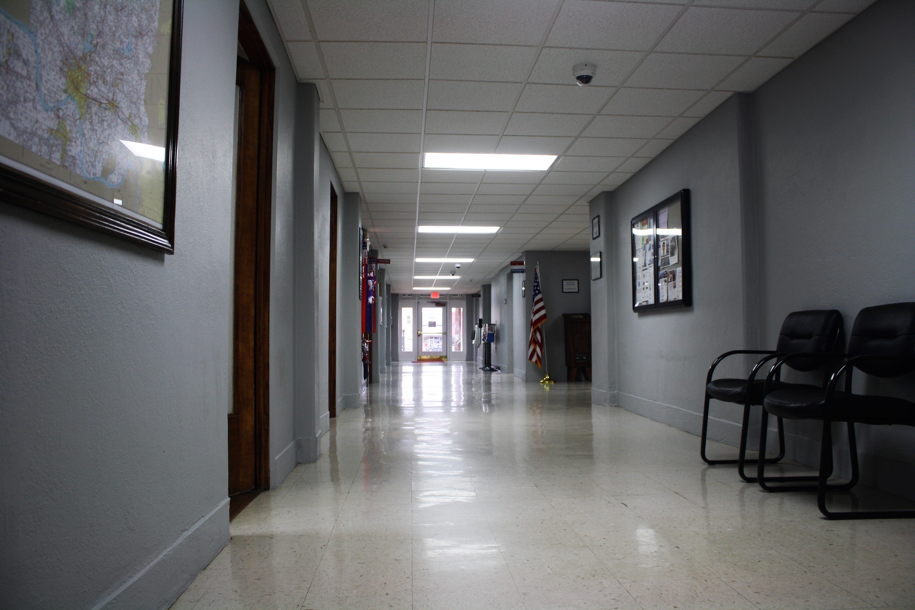 Quiet courthouse hallway with waiting chairs, office doors, and a clear route to the exit