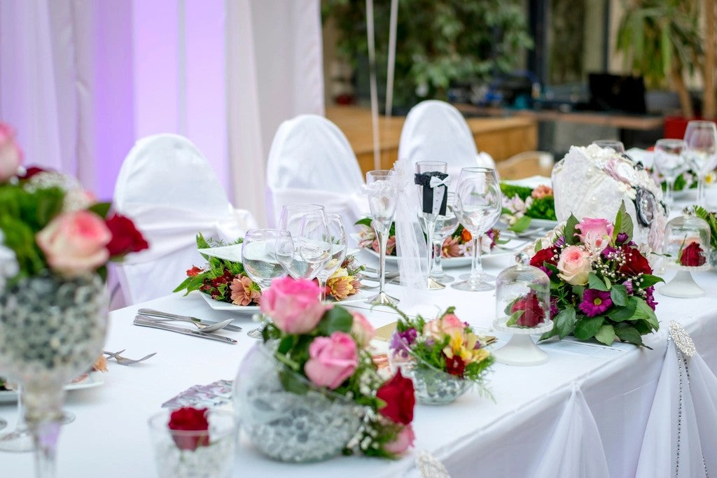 Wedding reception table set with flowers, glassware, and white chairs