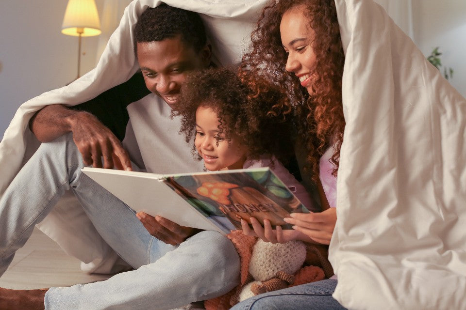 Two adults and a child sharing a quiet moment with a picture book at home