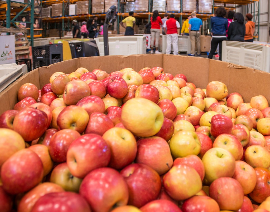 Apples in a food distribution warehouse with volunteers working in the background