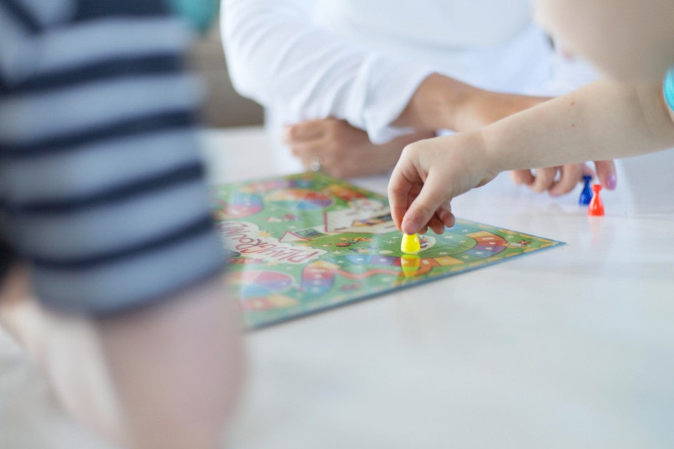 Friends gathered around a table playing a colorful board game at home