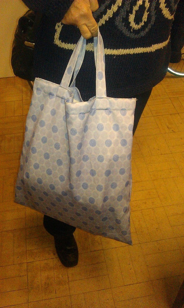 Person carrying reusable bags for a simple grocery pickup