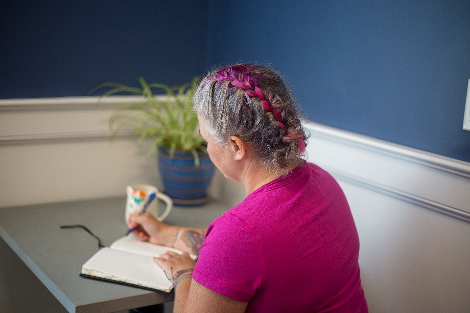 Person writing in a notebook at home for planning a gentle half-good day