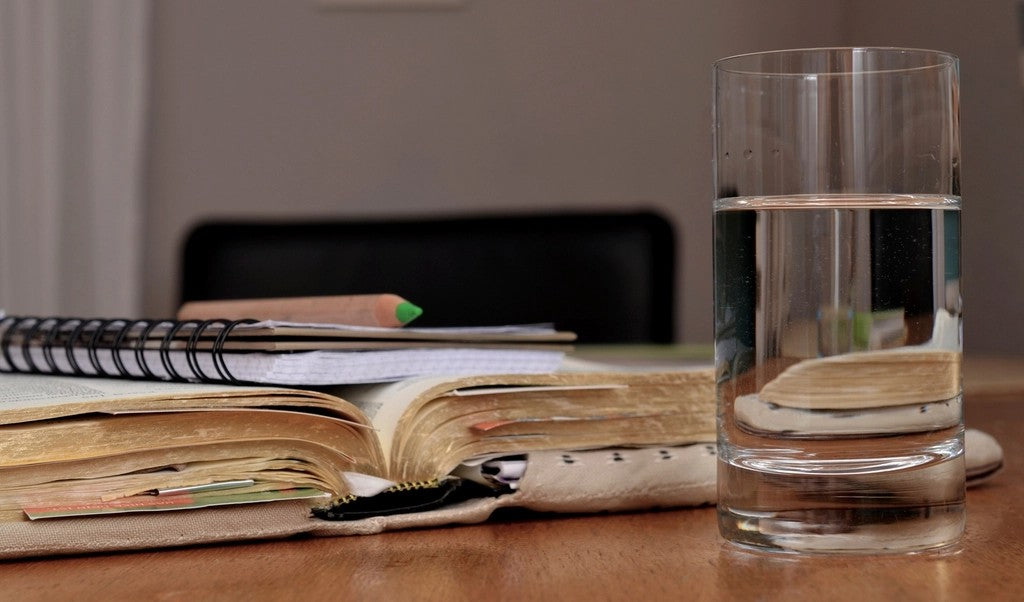 Glass of water beside open notebooks for planning a gentler hot day