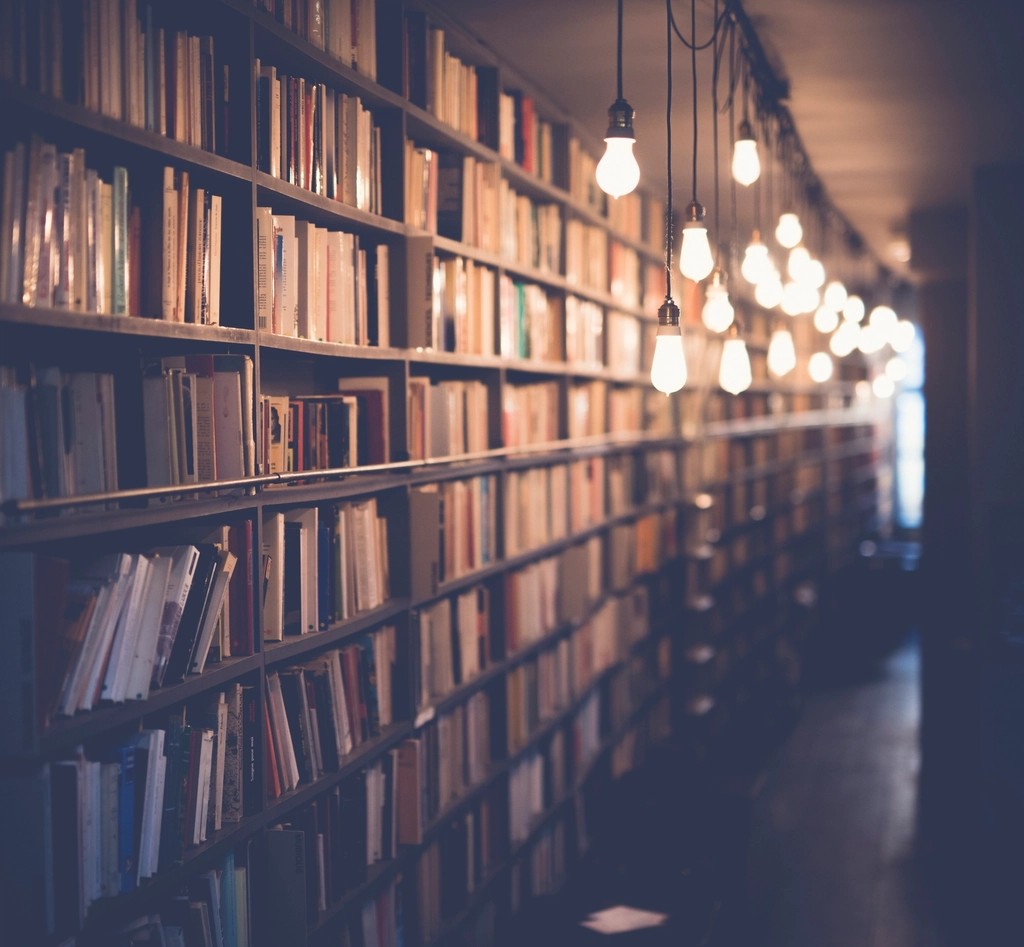 Warm hanging lights along a quiet aisle of library bookshelves