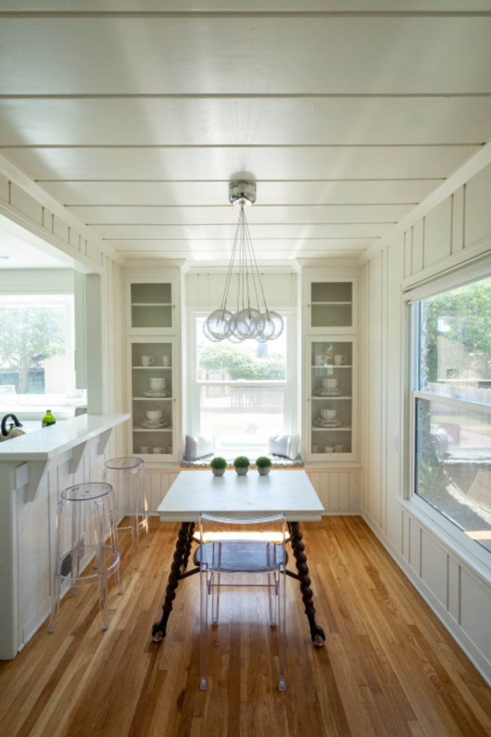 Bright home kitchen with counter stools, a chair, and a window bench