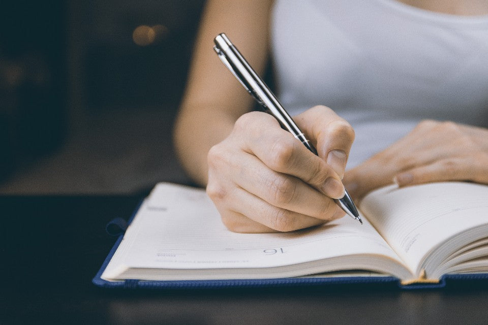 Person writing in a planner during a calm lower-pressure morning routine