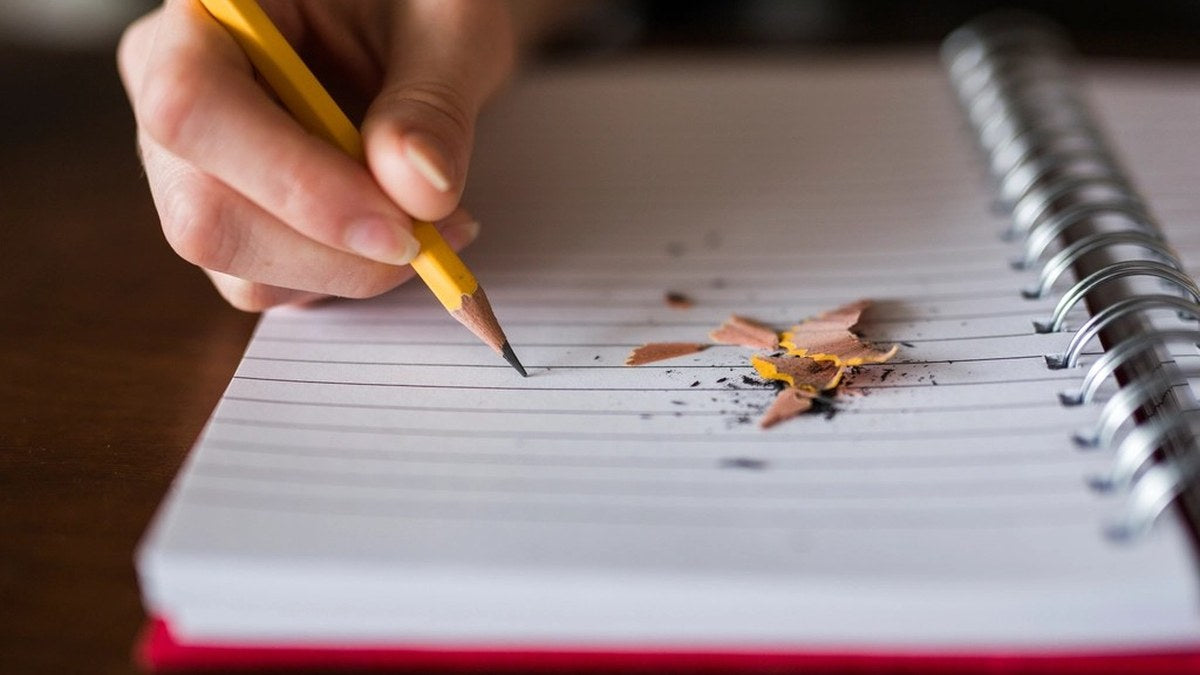 Person writing a one-page supplement list in a blank notebook