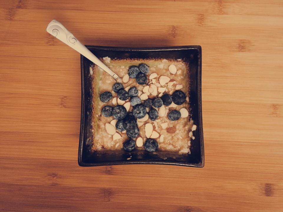 A warm bowl of oatmeal topped with fresh blueberries and sliced almonds on a wooden table