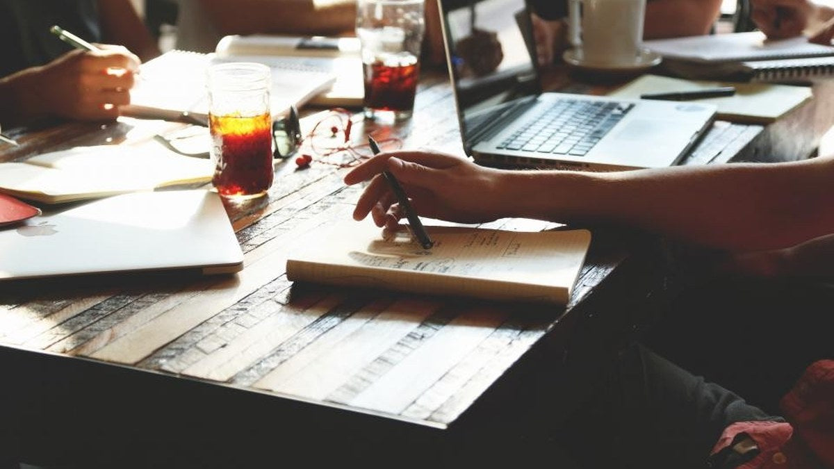 People gathered around a table with notebooks during a conversation