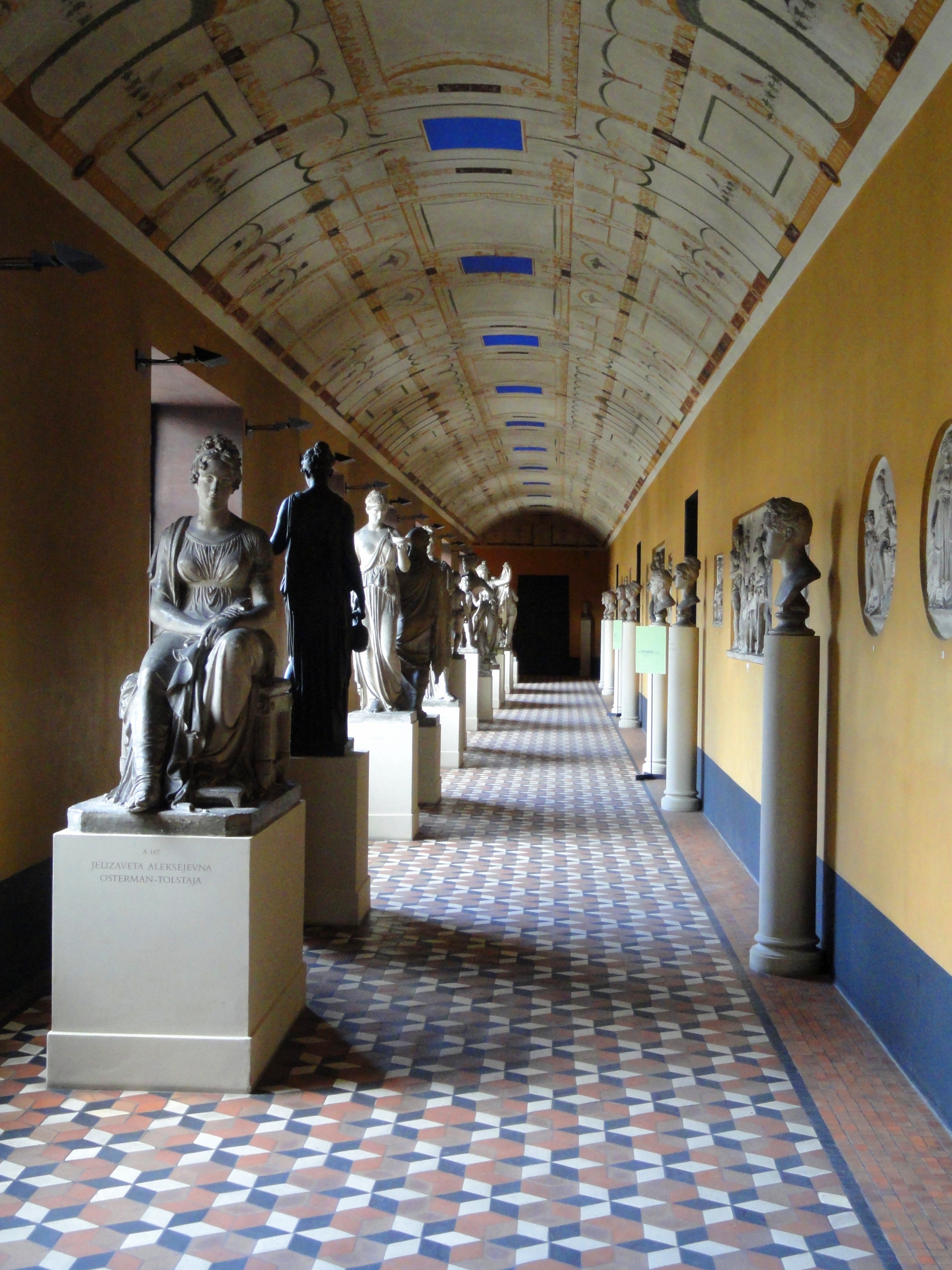 Quiet museum hallway lined with sculptures and a clear walking route