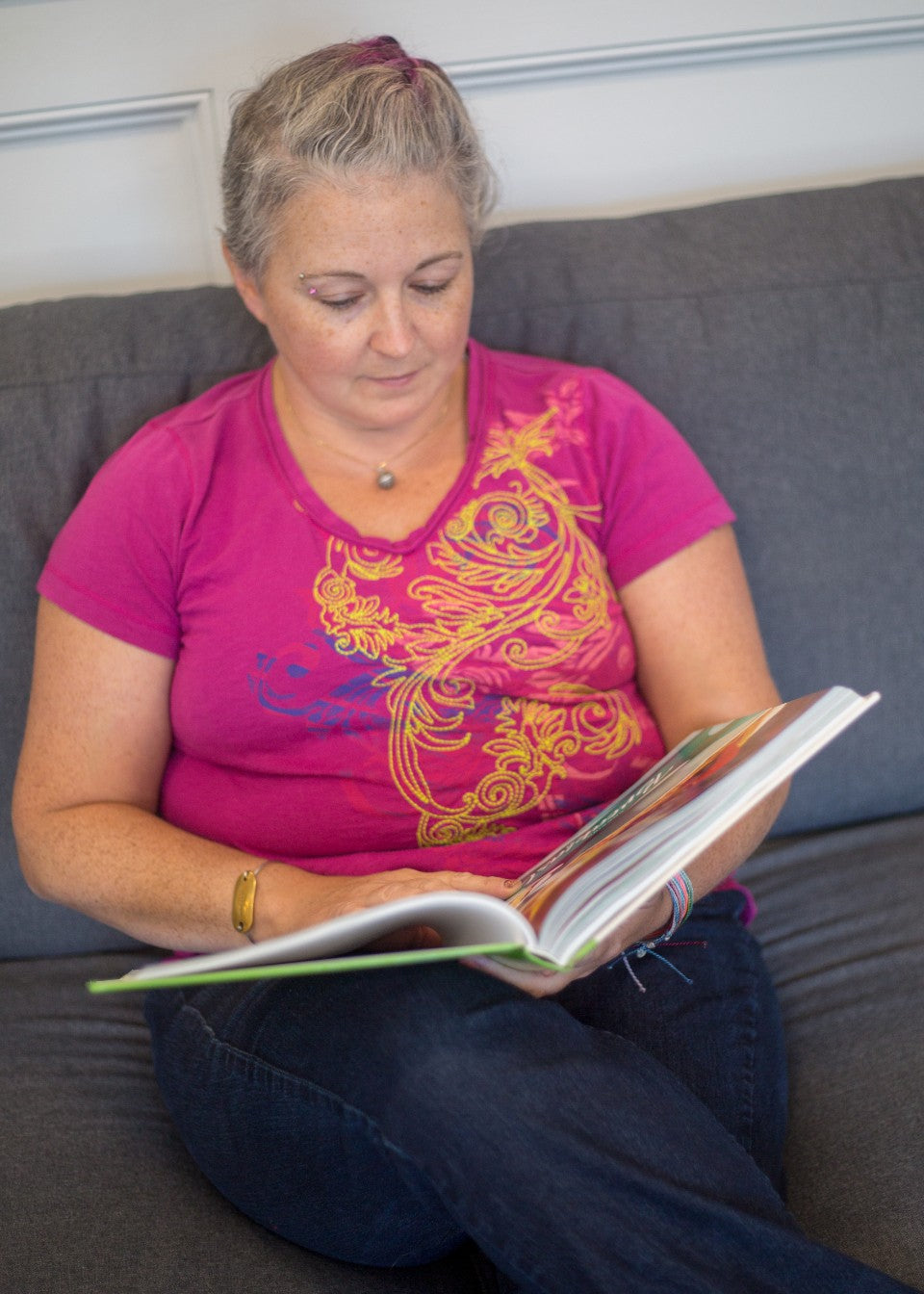 Woman sitting comfortably on a sofa and reading a large book