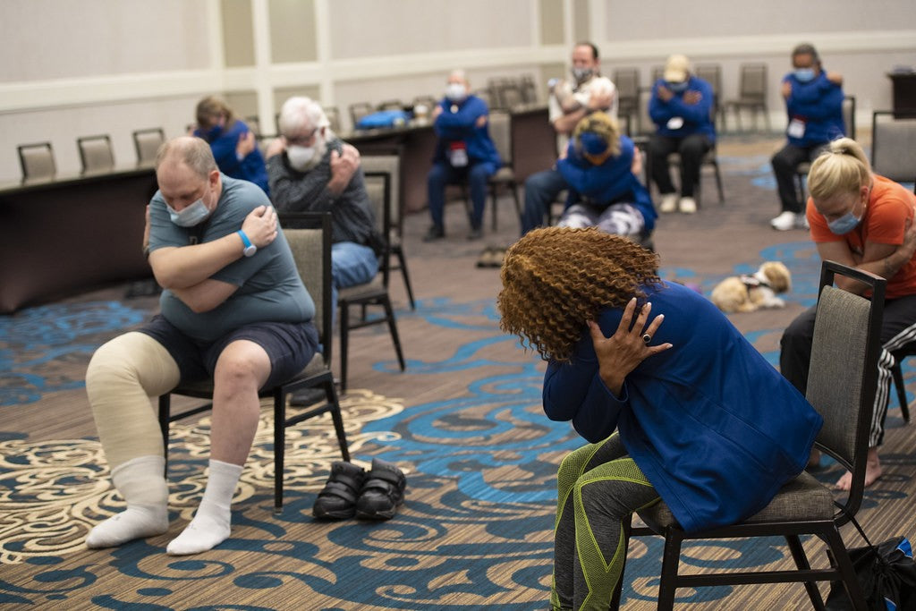 Adults taking part in a spaced, seated community movement class with room for modified participation