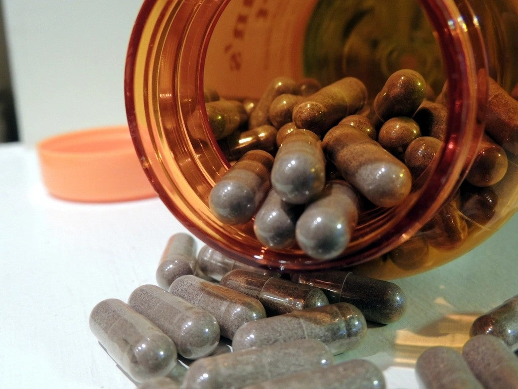Supplement capsules beside an unlabeled bottle on a clean surface