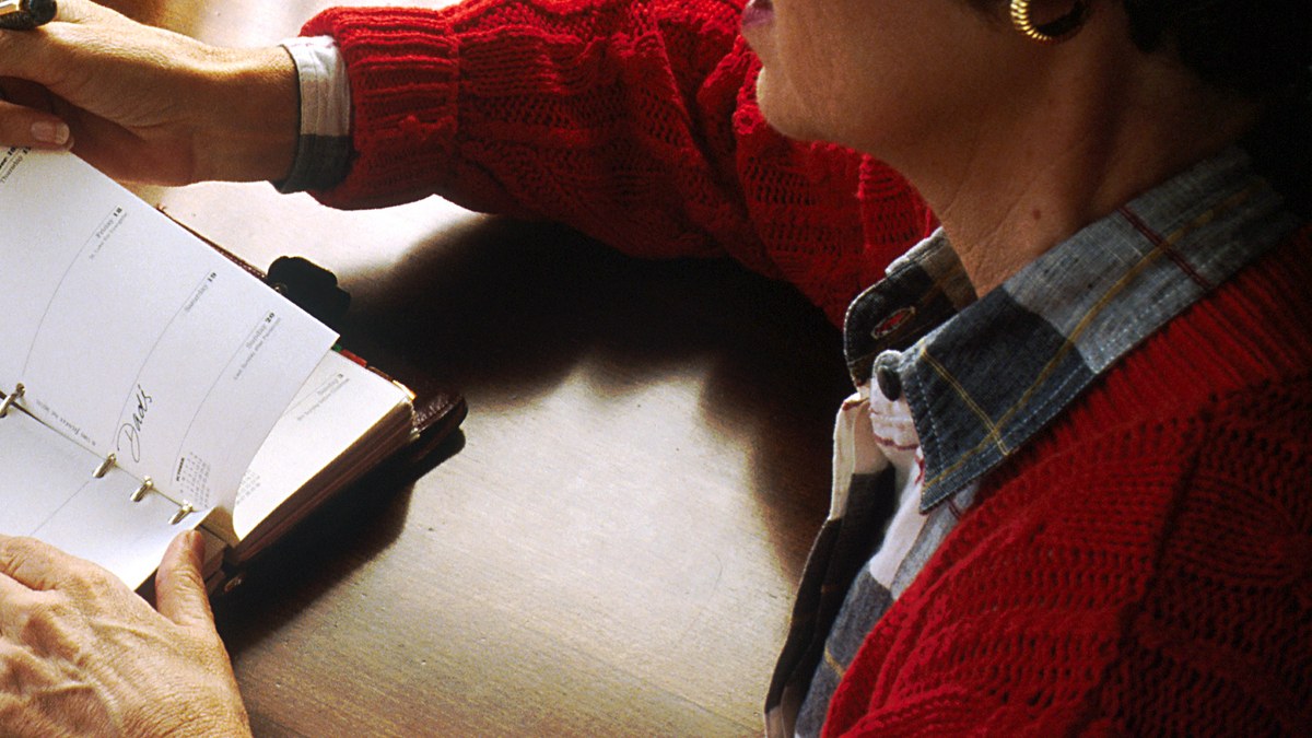 Person reviewing several entries in an open paper appointment book