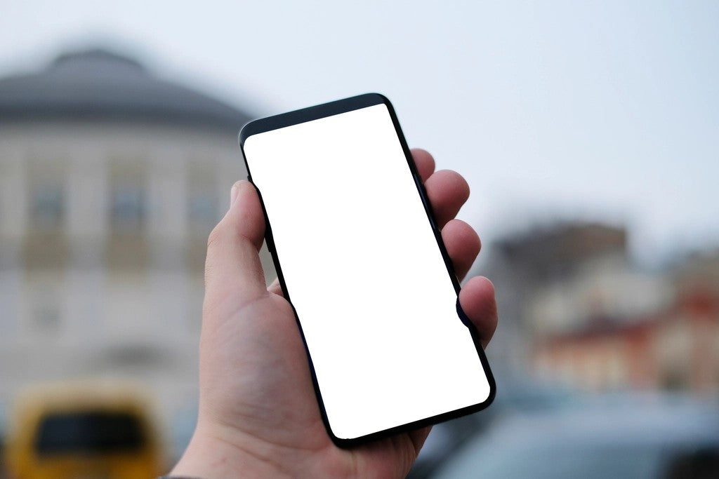 Hand holding a phone with a blank screen for saving a simple exit plan