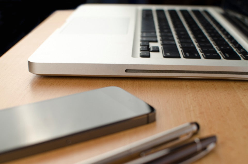Phone, laptop, and pens on a desk for keeping simple gut questions organized