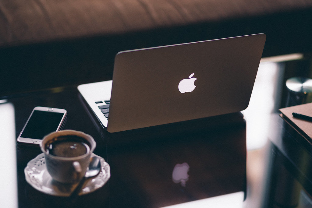 A laptop, phone, and cup of coffee arranged on a dark table for a quiet planning session