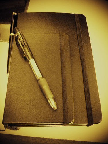 Closed notebook and pen for writing supplement questions before changing a routine