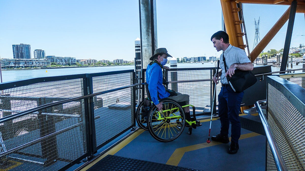 Gangway leading through a passenger ferry terminal as two adults speak near the boarding area