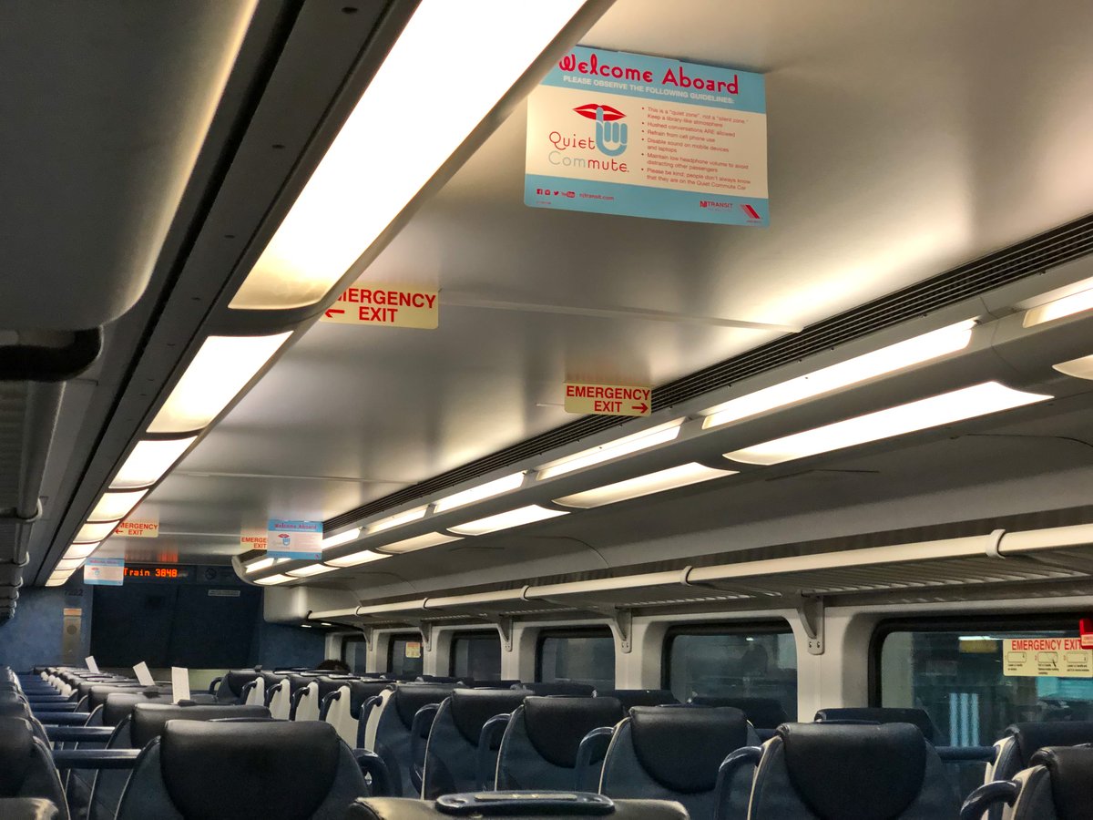 Interior of a clean passenger train car with rows of comfortable seats and a center aisle
