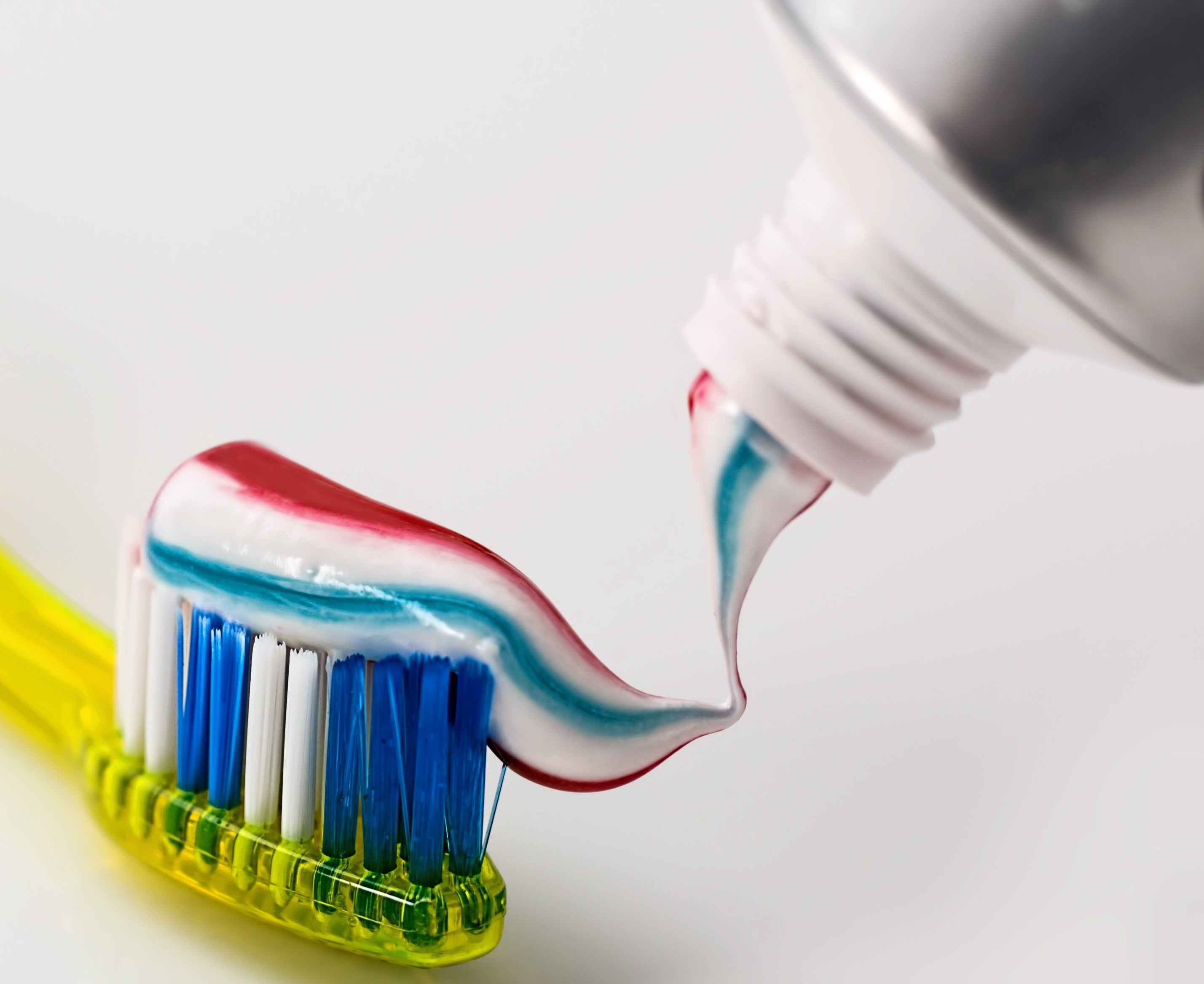 Colorful toothpaste being placed on a toothbrush before a dental visit