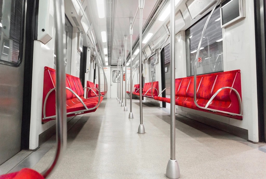 Empty metro carriage with red seats and a clear center aisle